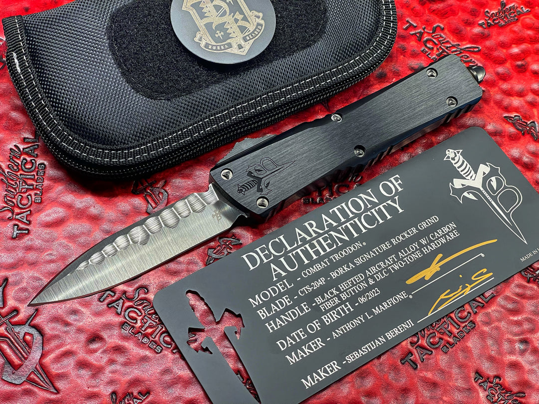 Marfione Custom Knives / Borka Blades Collaboration Combat Troodon, Chisel Grind, Borka Signature Rocker Grind, Black Hefted Aluminum Alloy Chassis, Carbon Fiber Button, DLC Two-Tone Hardware. DLC “Fuck Off” (Family Only) Pocket Clip. 1 of 3 Made.